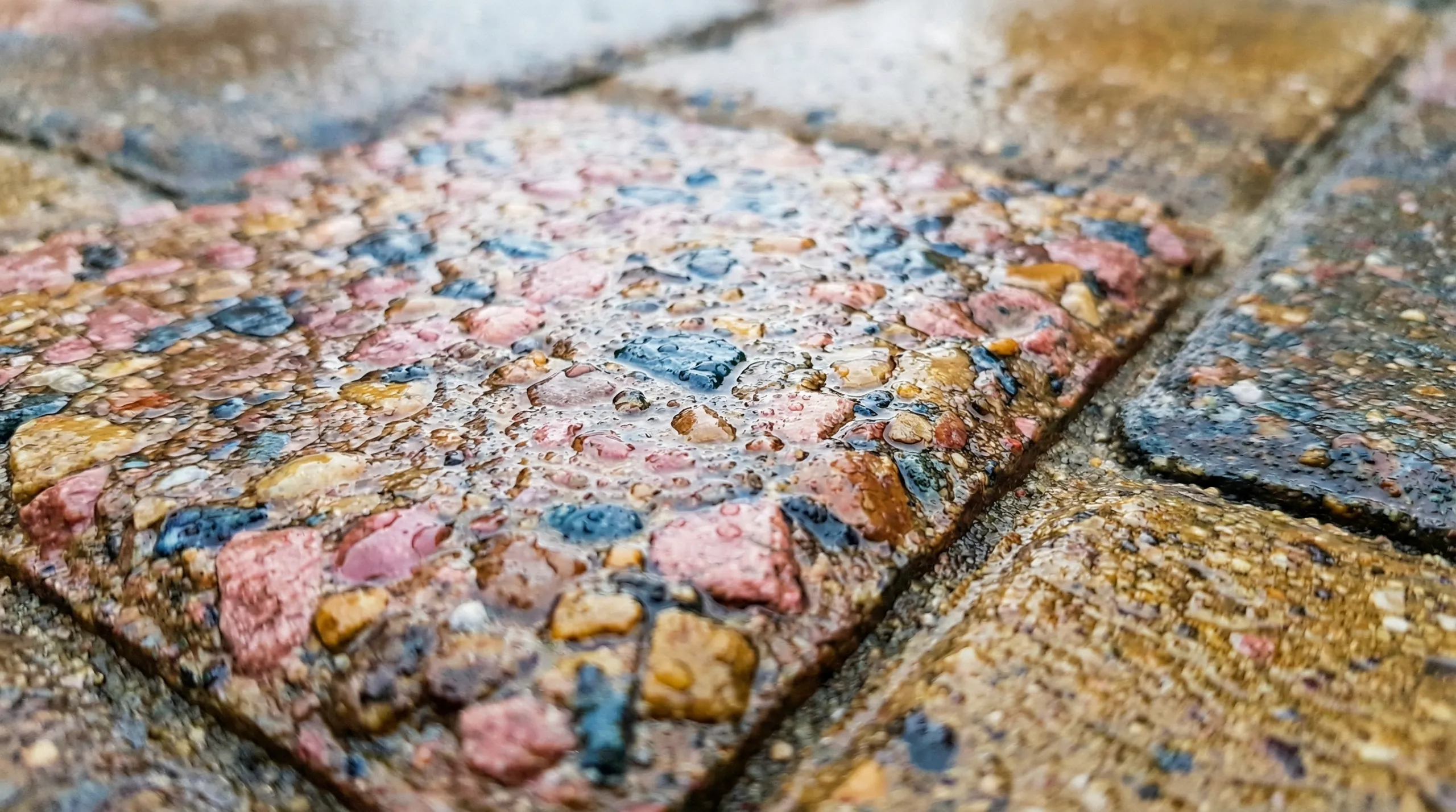 Zbliżenie mokrej, kolorowej kostki brukowej z widocznymi kroplami wody podczas mycia kostki brukowej